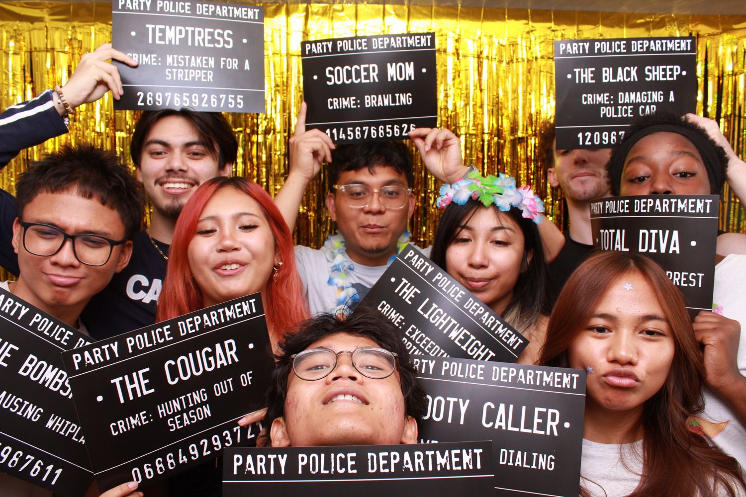 A group holding Party Police Department signs in front of a gold fringe curtain