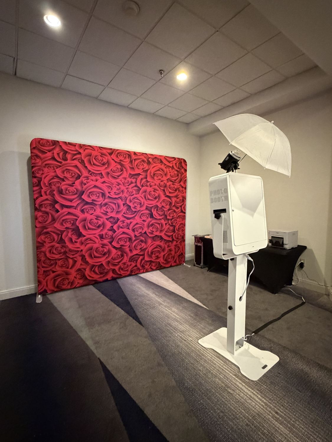 Photo booth and red roses backdrop in a carpeted meeting room